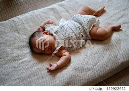 万歳の姿で寝る生後5ヶ月の日本人女の子の赤ちゃん	 129922631