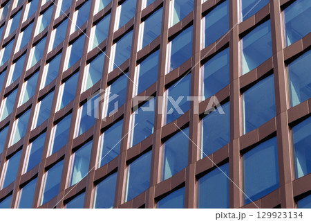 Modern office building facade with brown grid and glass windows Modern office building facade with brown grid and glass windows 129923134