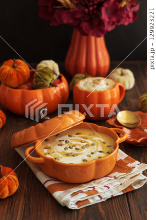 Autumnal lunch with pumpkin soup in a pumpkin-shaped bowl, pumpkin latte, croutons and festive decor on dark wooden table Autumnal lunch with pumpkin soup in a pumpkin-shaped bowl, pumpkin latte, croutons and festive decor on dark wooden table 129923221