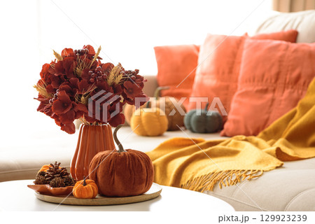 Thanksgiving living room decor with a coffee table, pumpkins and a floral arrangement. Thanksgiving living room decor with a coffee table, pumpkins and a floral arrangement. 129923239