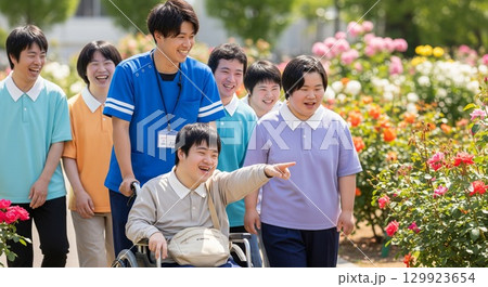 公園のバラ園で笑顔で過ごす車いすの障がい者と支援員の男性写真 129923654