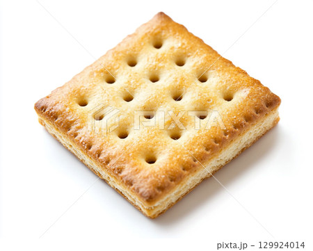 A close-up shot of a small pile of square creme crackers stacked against a plain white background. The crackers are golden-brown with small holes on their surface. 129924014