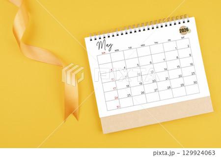 May 2026 desk calendar with yellow ribbon on yellow color background, Flat lay. May 2026 desk calendar with yellow ribbon on yellow color background, Flat lay. 129924063