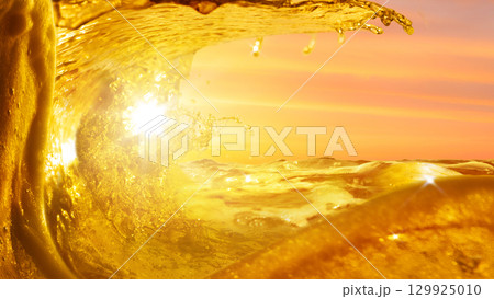 Golden beer splash wave glowing under sunset sky Golden beer splash wave glowing under sunset sky 129925010