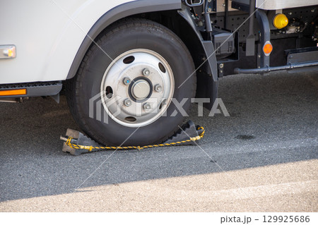 トラックの前輪に設置された輪止め 129925686