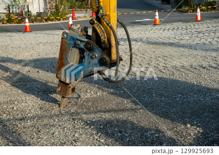 バックホウの先に取り付けられた油圧ブレーカー 129925693