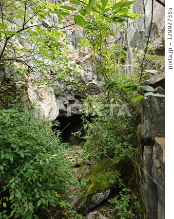 Mysterious Cave Entrance Surrounded by Lush Greenery and Rocky Cliffs, a Natural Wonder Scene Mysterious Cave Entrance Surrounded by Lush Greenery and Rocky Cliffs, a Natural Wonder Scene 129927385