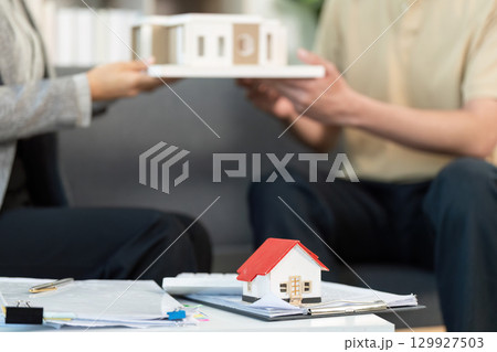 Real Estate Agent Presenting Model House to Client 129927503