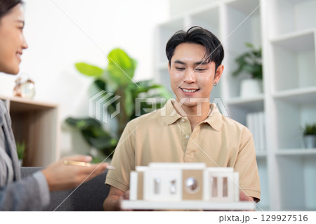 Real Estate Agent Smiling with Client Over Model House 129927516