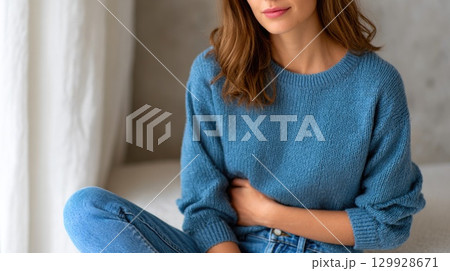 Woman in Blue Sweater Holding Stomach 129928671