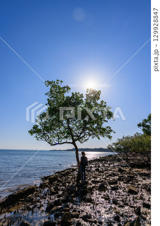 夕方のオーストラリア、ダーウインのRAMEROO BEACHの木の下に立つ女性 129928847