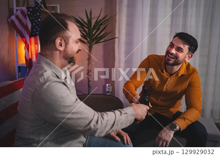Friends celebrating a joyful moment together in a cozy living room during a fun evening gathering 129929032