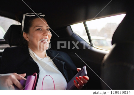 Smiling woman relaxing in a car during a sunny afternoon drive 129929034