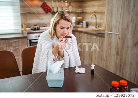 Cozy winter morning with a woman sipping tea in a warm kitchen 129929072