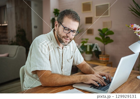 Focused individual working at a wooden desk indoors 129929131