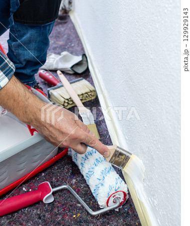 House painter worker painting a wall white. Building. 129929143