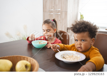 Multiracial siblings enjoying breakfast at home on a sunny morning 129929163