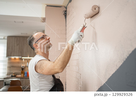 Man Painting a Wall With a Paint Roller 129929326