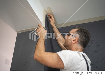 Man sticks protective tape on the wall before painting 129929331