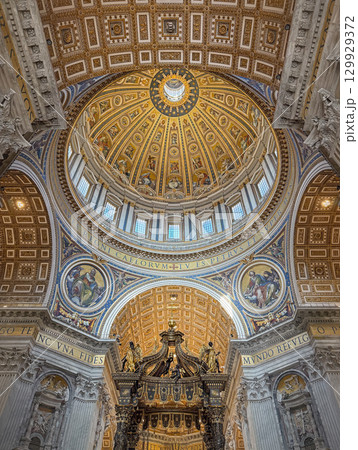 Ornate, gilded dome and ceiling of St. Peter's Basilica, features a golden sunburst design, decorated with intricate mosaics and paintings. Luxurious decoration of the Vatican iconic interior Ornate, gilded dome and ceiling of St. Peter's Basilica, features a golden sunburst design, decorated with intricate mosaics and paintings. Luxurious decoration of the Vatican iconic interior 129929372