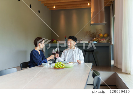 モダンなリビングダイニングで赤ワインを飲む夫婦 129929439