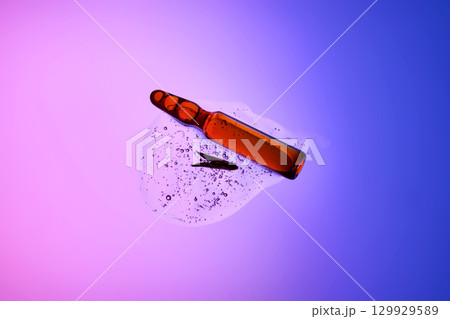An ampoule with serum in its texture on a purple background with a leaf. An ampoule with serum in its texture on a purple background with a leaf. 129929589