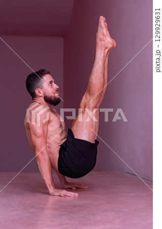 Man performs advanced core balance on hands with legs extended. Concept of strength, stability, discipline, control, endurance and physical mastery. Man performs advanced core balance on hands with legs extended. Concept of strength, stability, discipline, control, endurance and physical mastery. 129929631