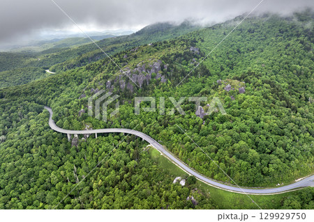 Winding mountain road in summer woods. Linn Cove Viaduct in Appalachian mountains in North Carolina with fresh green forest trees in summertime season. Beauty of USA nature Winding mountain road in summer woods. Linn Cove Viaduct in Appalachian mountains in North Carolina with fresh green forest trees in summertime season. Beauty of USA nature 129929750