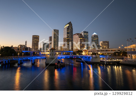 Night urban landscape of downtown district of Tampa in Florida, USA. American city skyline with brightly illuminated high commercial buildings and bridge over Hillsborough river. Night urban landscape of downtown district of Tampa in Florida, USA. American city skyline with brightly illuminated high commercial buildings and bridge over Hillsborough river. 129929812