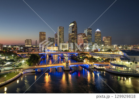 American city skyline with brightly illuminated high commercial buildings and bridge over Hillsborough river. Night urban landscape of downtown district of Tampa in Florida, USA. 129929818