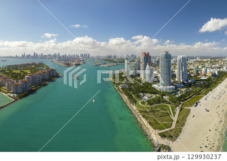 Tourism infrastructure in southern USA. South Beach sandy surface with tourists relaxing on hot Florida sun. Miami Beach city with high luxury hotels and condos 129930237