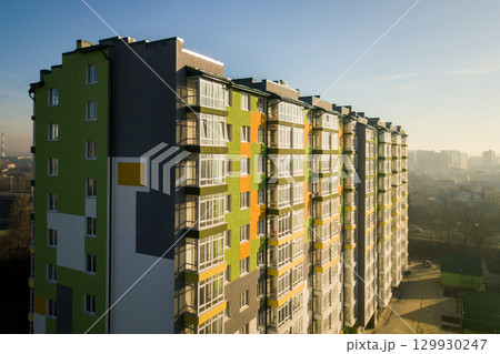 Aerial view of a tall residential apartment building with many windows and balconies. Aerial view of a tall residential apartment building with many windows and balconies. 129930247
