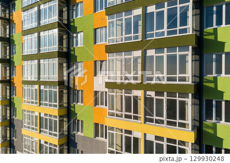 Aerial view of a tall residential apartment building with many windows and balconies. 129930248