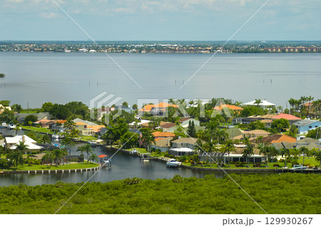 Aerial view of rural private houses in remote suburbs located on sea coast near Florida wildlife wetlands with green vegetation on gulf bay shore. Living close to nature in tropical region concept 129930267