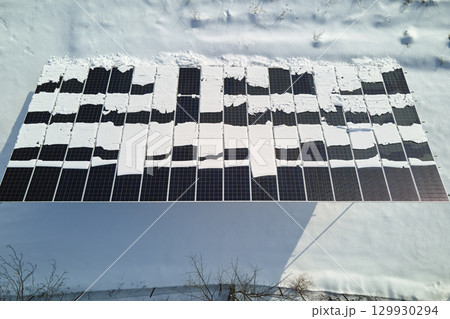 Aerial view of snow melting from covered solar photovoltaic panels at sustainable electric power plant for producing clean electrical energy. Low effectivity of renewable electricity in winter 129930294