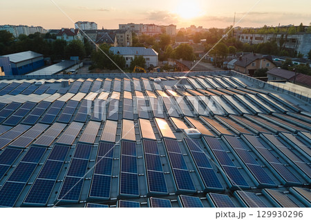 Blue photovoltaic solar panels mounted on building roof for producing clean ecological electricity at sunset. Production of renewable energy concept 129930296