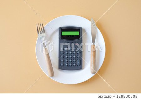 Calorie counting,Calculator in plate with a fork and a knife . Calorie counting,Calculator in plate with a fork and a knife . 129930508