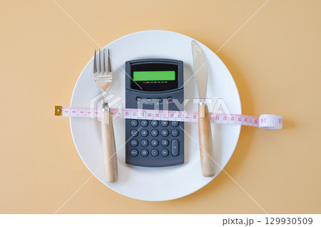 Calorie counting,Calculator in plate with a fork and a knife . Calorie counting,Calculator in plate with a fork and a knife . 129930509