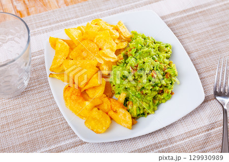 Beer snacks are laid out on plate - chips and portion of thick pasta sauce guacamole Beer snacks are laid out on plate - chips and portion of thick pasta sauce guacamole 129930989