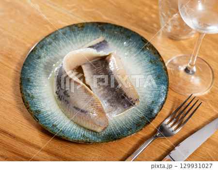 Pieces of pickled herring served on platter 129931027