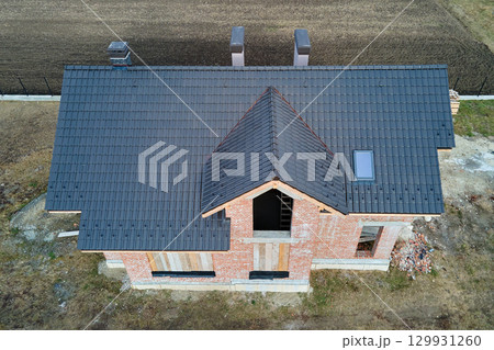 Aerial view of house roof top covered with ceramic shingles. Tiled covering of building under construction 129931260