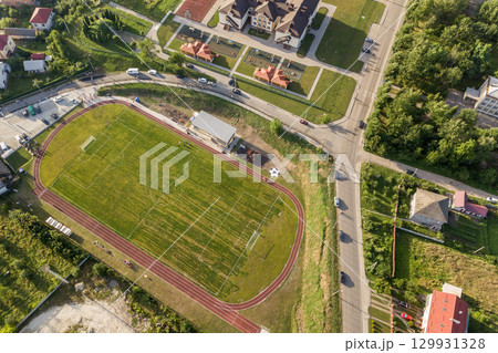 Aerial view of a football field on a stadium covered with green grass in rural town area. Aerial view of a football field on a stadium covered with green grass in rural town area. 129931328