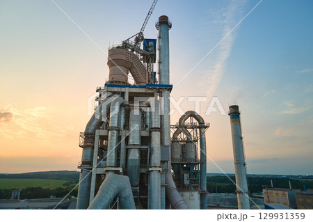 Cement plant with high factory structure and tower cranes at industrial production area. Manufacture and global industry concept Cement plant with high factory structure and tower cranes at industrial production area. Manufacture and global industry concept 129931359