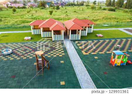 Aerial view of new alcove in kindergarten play yard with red tiled roof for outdoor children activities. 129931361