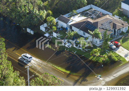 Flooded Florida road with evacuating cars and surrounded with water houses in suburban residential area. Consequences of hurricane natural disaster Flooded Florida road with evacuating cars and surrounded with water houses in suburban residential area. Consequences of hurricane natural disaster 129931392