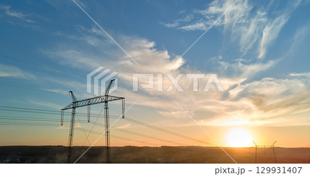 Dark silhouette of high voltage tower with electric power lines at sunrise. Transmission of electric energy concept Dark silhouette of high voltage tower with electric power lines at sunrise. Transmission of electric energy concept 129931407
