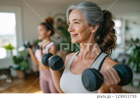 Women Actively Engaged in Strength Training with Dumbbells in the Comfort of Their Home 129931730