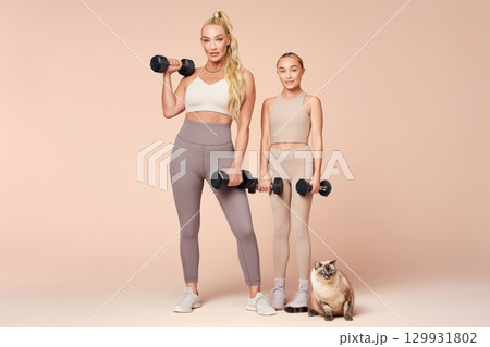 A Mother and Daughter enjoy a fun Workout with Dumbbells and their Pet, bonding through fitness 129931802
