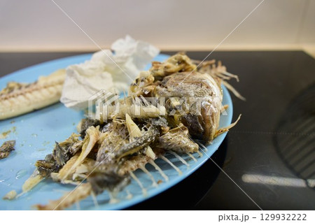 Dorado fish is presented on a blue plate, showcasing only its bones and remnants after being eaten 129932222