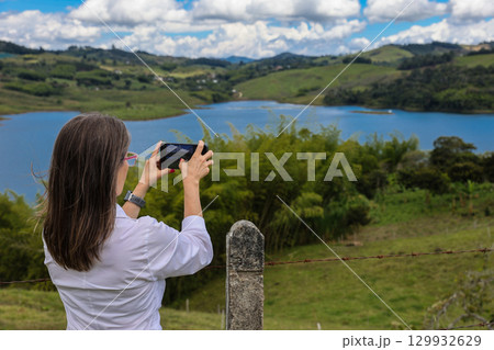 Female tourist taking pictures at the biggest artificial lake in Colombia called Calima Lake located on the mountains of Darien at the region of Valle del Cauca 129932629